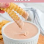 Two French fries dipped in homemade Raising Cane's sauce.