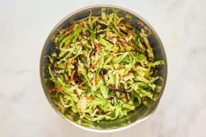 Shredded cabbage and vegetables for sweet and sour coleslaw in a large bowl.