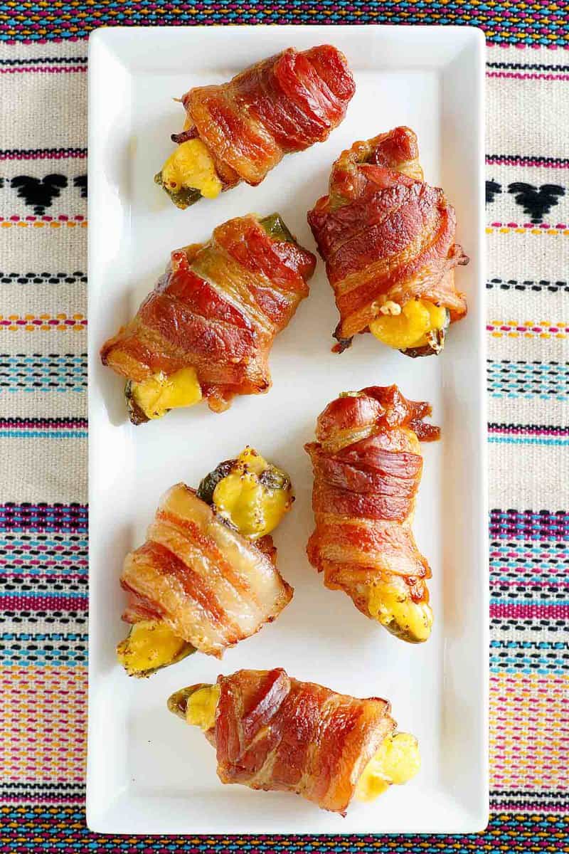 Overhead view of air fryer bacon wrapped jalapeno poppers on a platter.