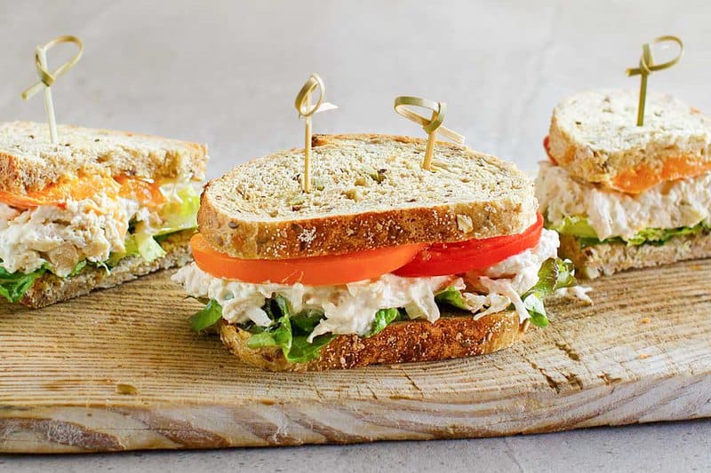 Sandwiches made with copycat Chicken Salad Chick Classic Carol chicken salad on a wood board.