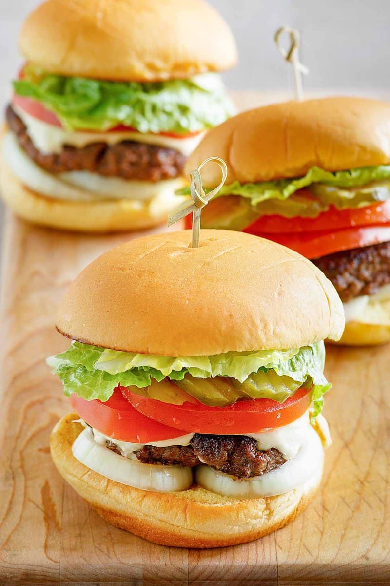 Three copycat Culver's butter burgers on a wood serving board.