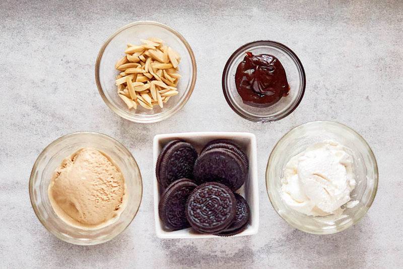 Ice cream mud pie ingredients in bowls on parchment paper.