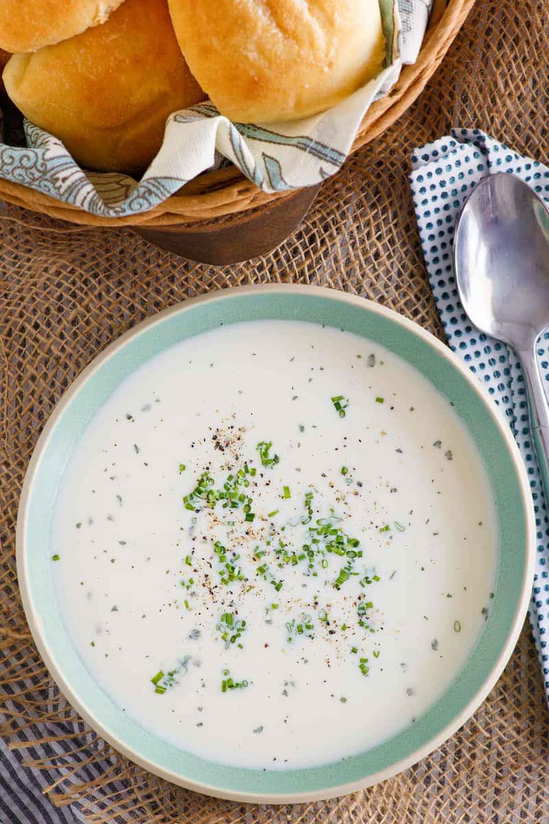 Overhead view of Grandma's old-fashioned potato soup, a spoon, and rolls.