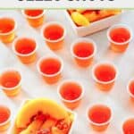 Peach jello shots in plastic cups and peach slices in bowls.
