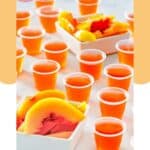Peach jello shots in plastic shot cups and peach slices.