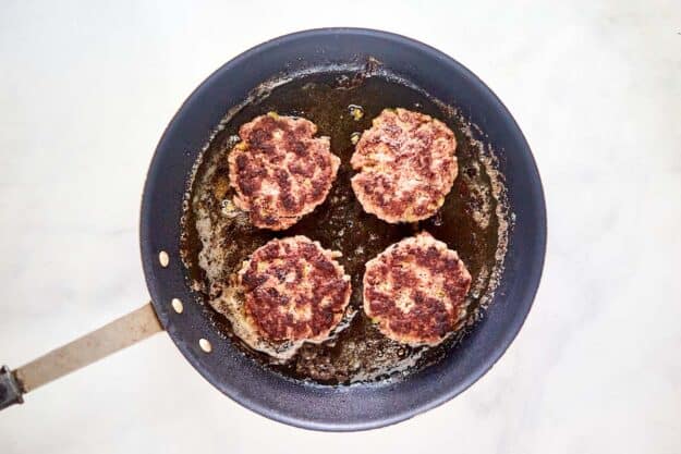 Cooked 21 Club burger patties in a skillet.