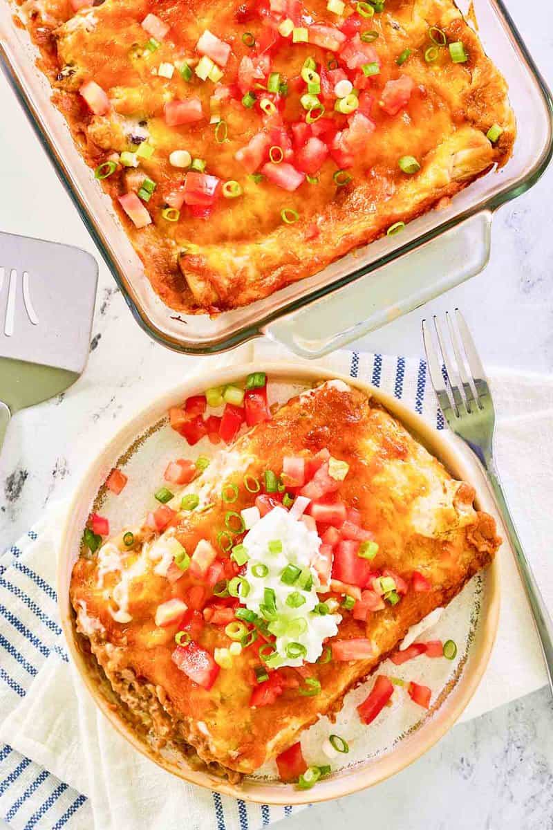 Overhead view of burrito casserole in a baking dish and on a plate.