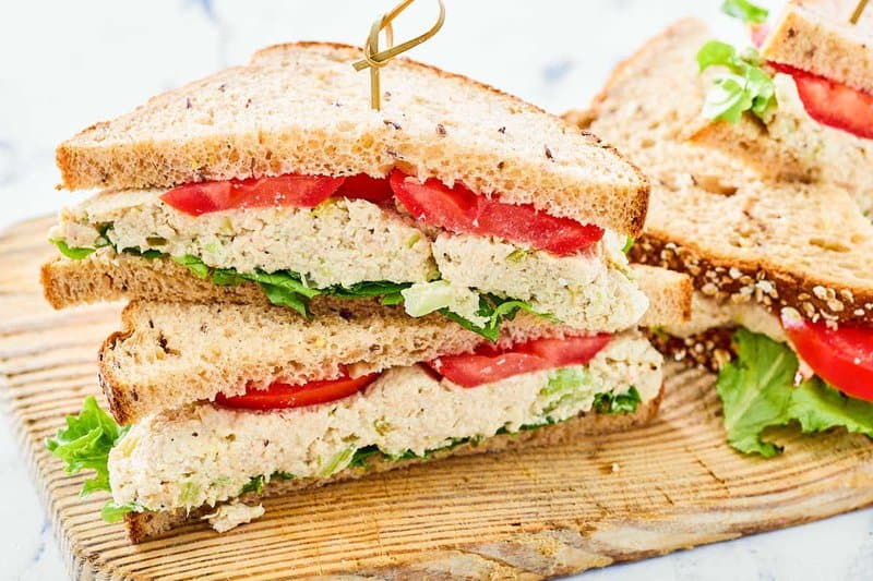Copycat Chick Fil A chicken salad sandwich with honey wheat bread, lettuce, and tomato.