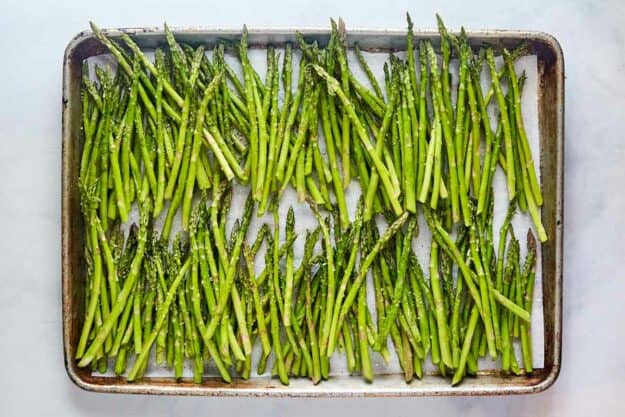 Fresh asparagus spears on a baking sheet.