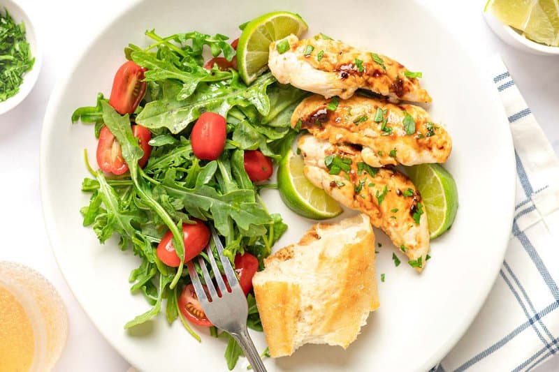 Copycat Cracker Barrel grilled chicken tenders, a salad, and bread on a plate.