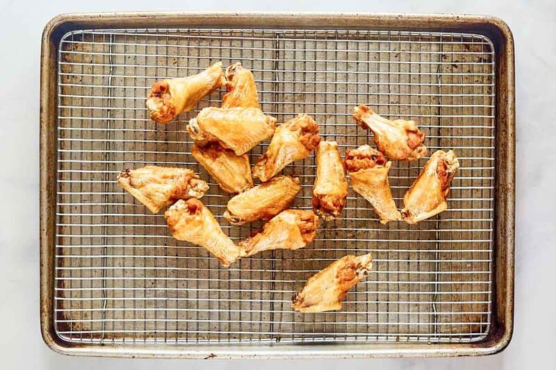 Deep fried chickenhearted  wings draining connected  a ligament  rack implicit    a baking sheet.