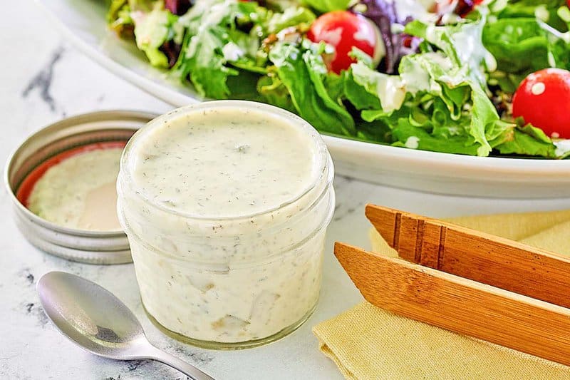 Homemade dill pickle ranch dressing on a salad and in a small mason jar.