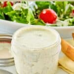 Dill pickle ranch dressing in a small mason jar and on a salad behind it.