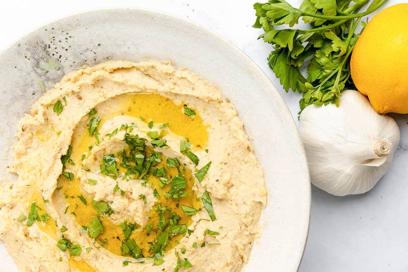 Homemade garlic hummus, fresh parsley, lemon, and garlic bulb.