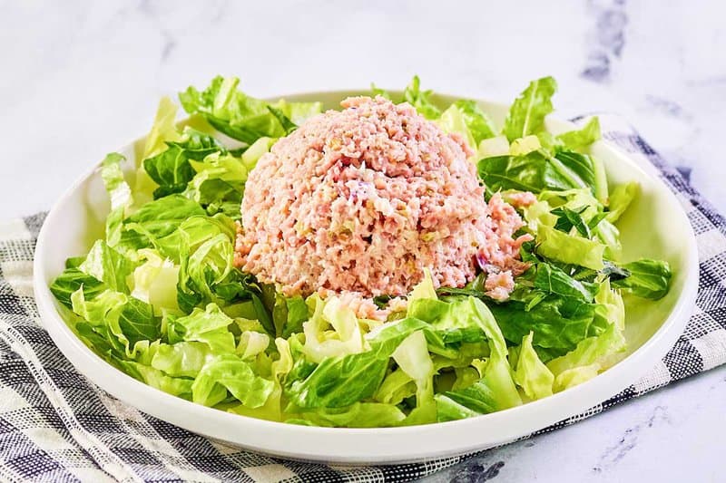 A scoop of ham salad on top of lettuce.