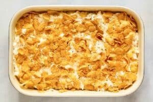 Hashbrown casserole mixture topped with cornflakes before baking.