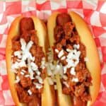 Two hot dogs topped with copycat James Coney Island chili and chopped onions.