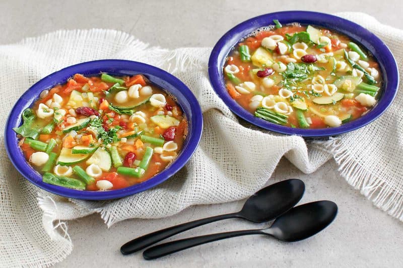 Copycat Olive Garden minestrone soup in two bowls and two spoons.