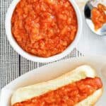 Overhead view of homemade Sabrett onion sauce in a bowl and on a hot dog.
