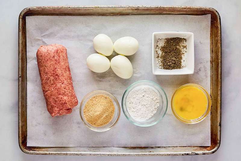 Scotch eggs ingredients on a tray.