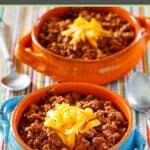 Copycat Wick Fowler 2 alarm chili topped with shredded cheese in two bowls.