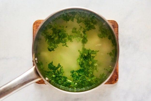 Potatoes, fresh parsley, and water in a pot.