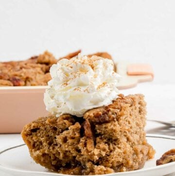 Cinnamon coffee cake slice with whipped cream on top.