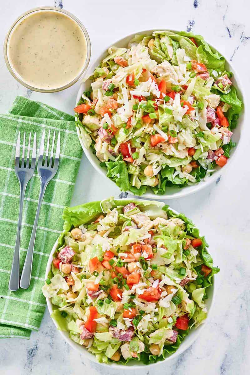 Copycat Cucina Cucina chopped salad in two bowls and dressing in a small bowl.