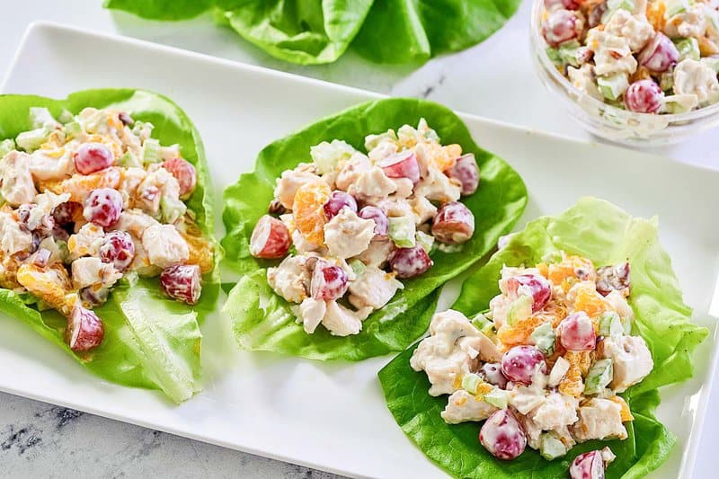 Fruity chicken salad with mandarin oranges, grapes, celery, and nuts on a platter.