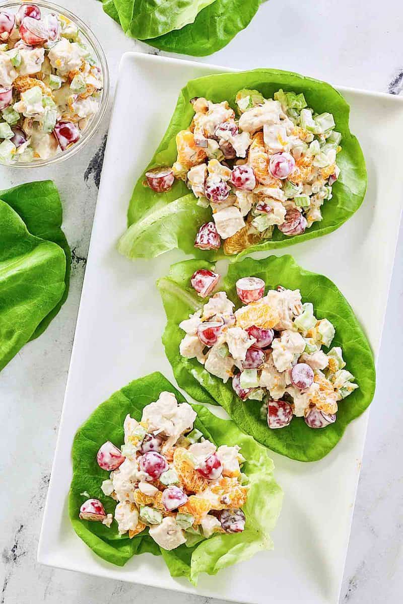 Fruity chicken salad on butter lettuce leaves on a platter.