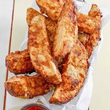 Jojo potato wedges in a serving basket and a cup of ketchup beside it.