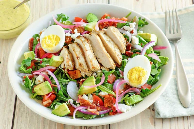 Copycat Panera chicken cobb salad, green goddess dressing, and a fork on a napkin.