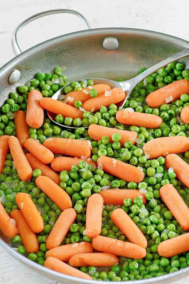 Buttery peas and carrots in a skillet.