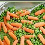 Buttery peas and carrots in a stainless steel skillet.