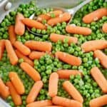 Freshly made buttery peas and carrots in a skillet.