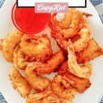 Beer battered deep fried shrimp and a bowl of dipping sauce on a plate.