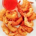 Beer battered fried shrimp and a bowl of dipping sauce on a plate.