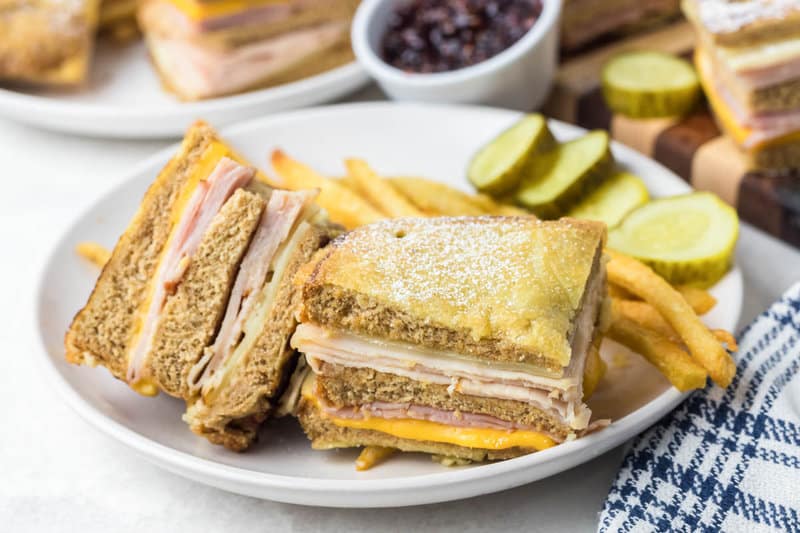 Copycat Bennigan's Monte Cristo sandwich, fries, and pickle slices on a plate.