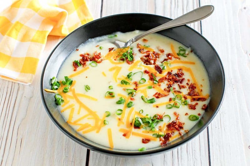 Copycat Bennigan's ultimate baked potato soup topped with bacon, cheese, and green onions.