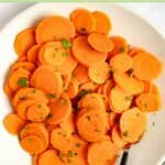 Sliced boiled carrots garnished with fresh parsley on a plate.