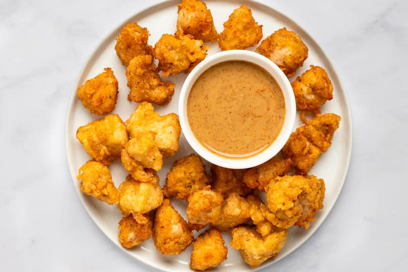Copycat Chick Fil A chicken nuggets and a bowl of dipping sauce on a plate.