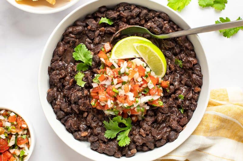 Copycat Chili's black beans topped with pico de gallo and lime wedges.