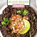 A bowl of homemade Chili's black beans with lime wedges and pico de gallo on top.