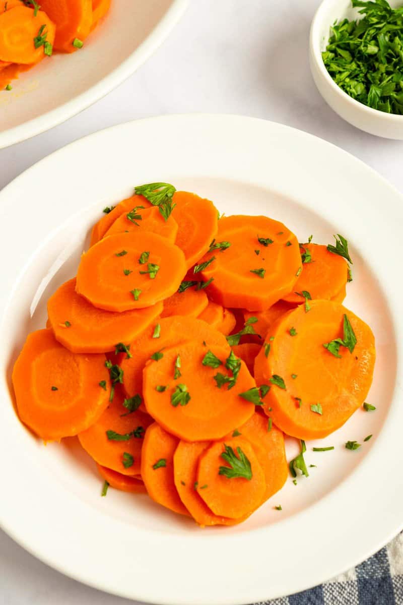 Cooked carrots on a plate garnished with fresh parsley.