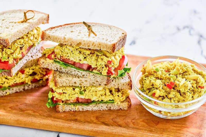 A bowl of curried chicken salad and two sandwiches.