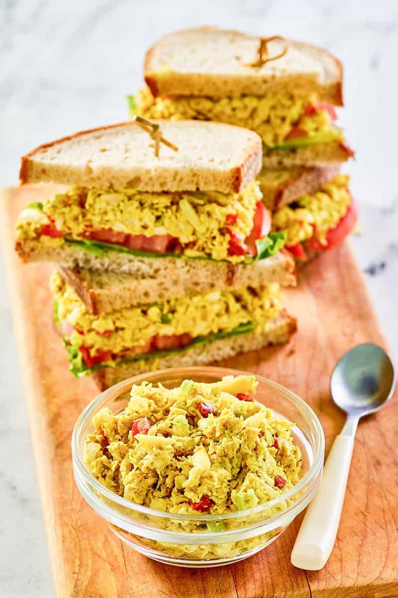 Curried chicken salad sandwiches, the salad in a small bowl, and a spoon.