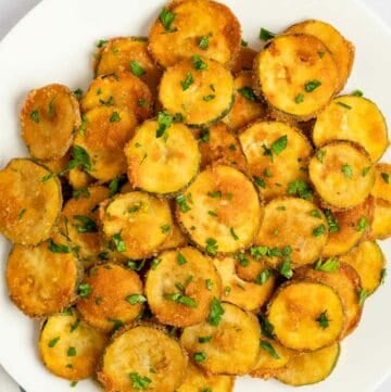 Fried zucchini garnished with parsley on a platter.