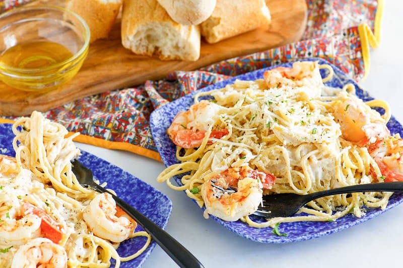 Copycat Olive Garden shrimp alfredo and forks on two plates.