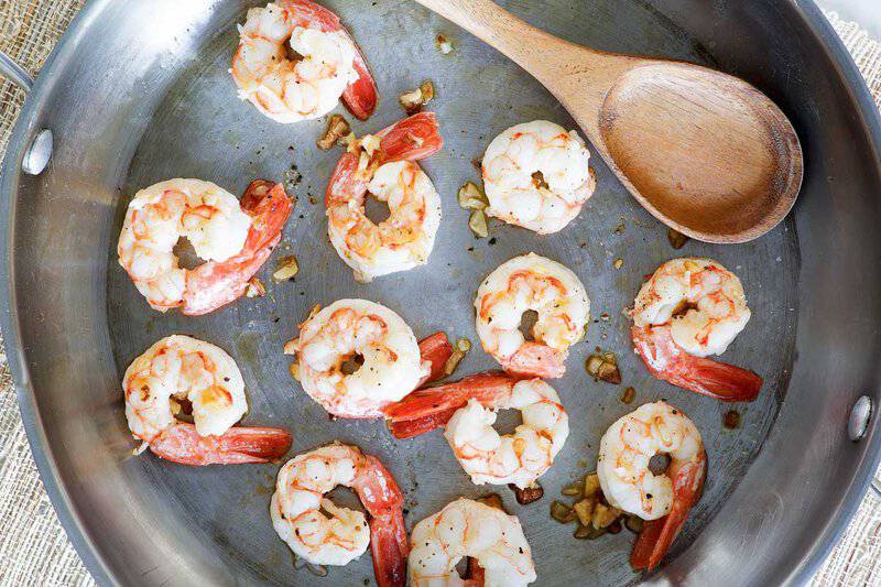Cooking shrimp in a skillet to make shrimp alfredo.