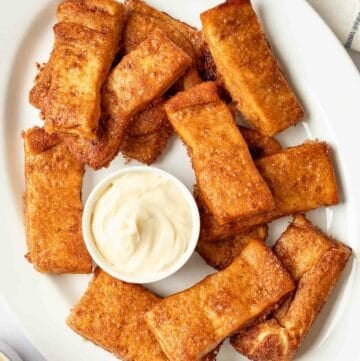 Copycat Pizza Hut Cinnamon Sticks and a bowl of cream cheese icing on a platter.